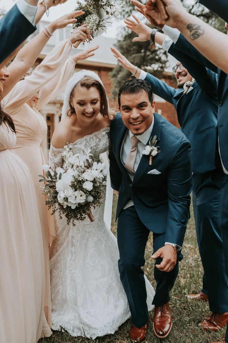 Bridal party cheering as the couple walks past, hands raised