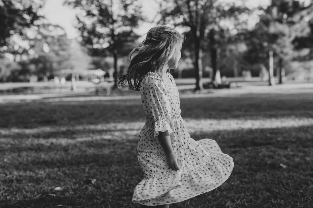 Little girl twirling in a park, black and white
