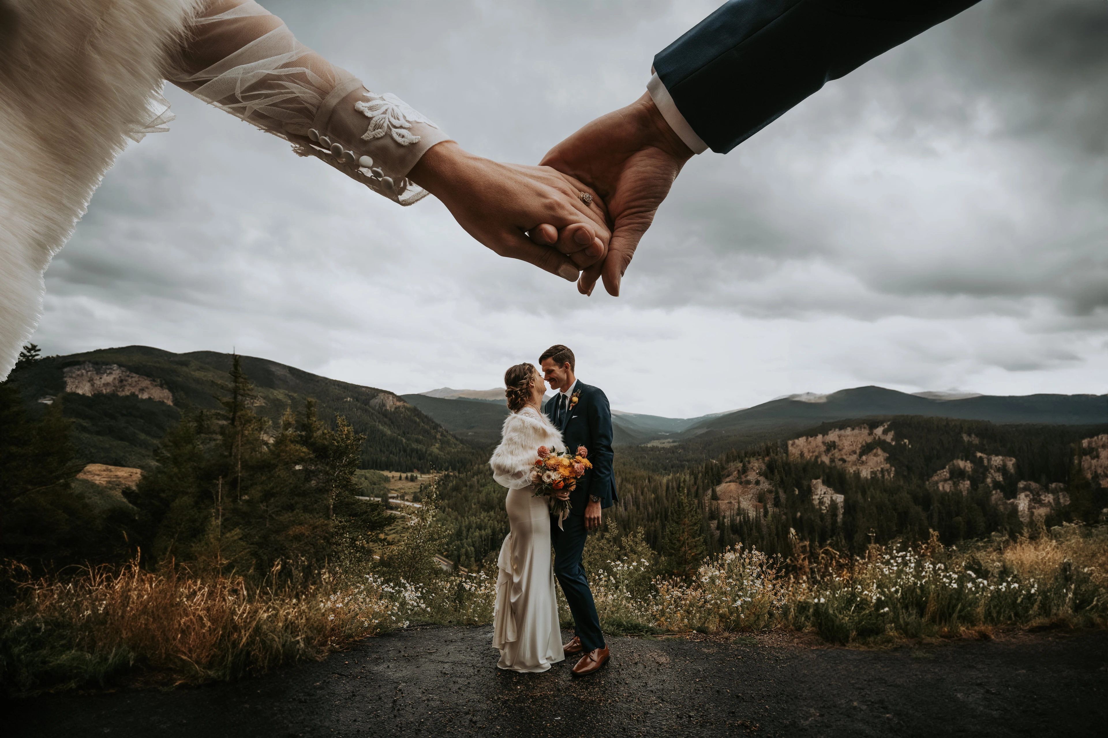 Bride and groom holding hands with mountain views in the distance