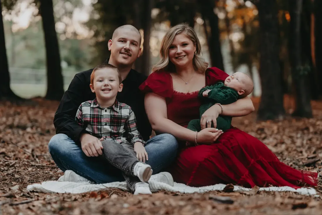 Family of six sitting together in autumn leaves
