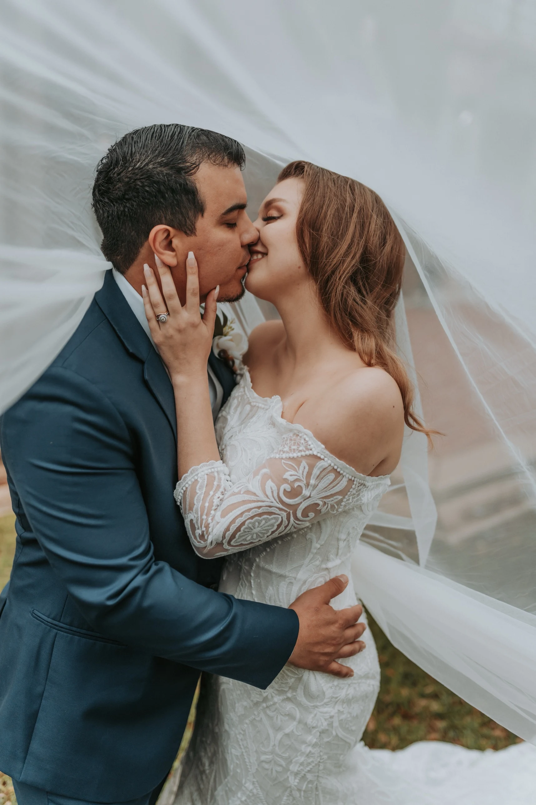 Bride and groom kissing under the veil, close-up