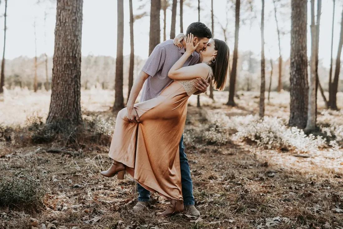 Engagement session, couple sharing a dip kiss in the woods