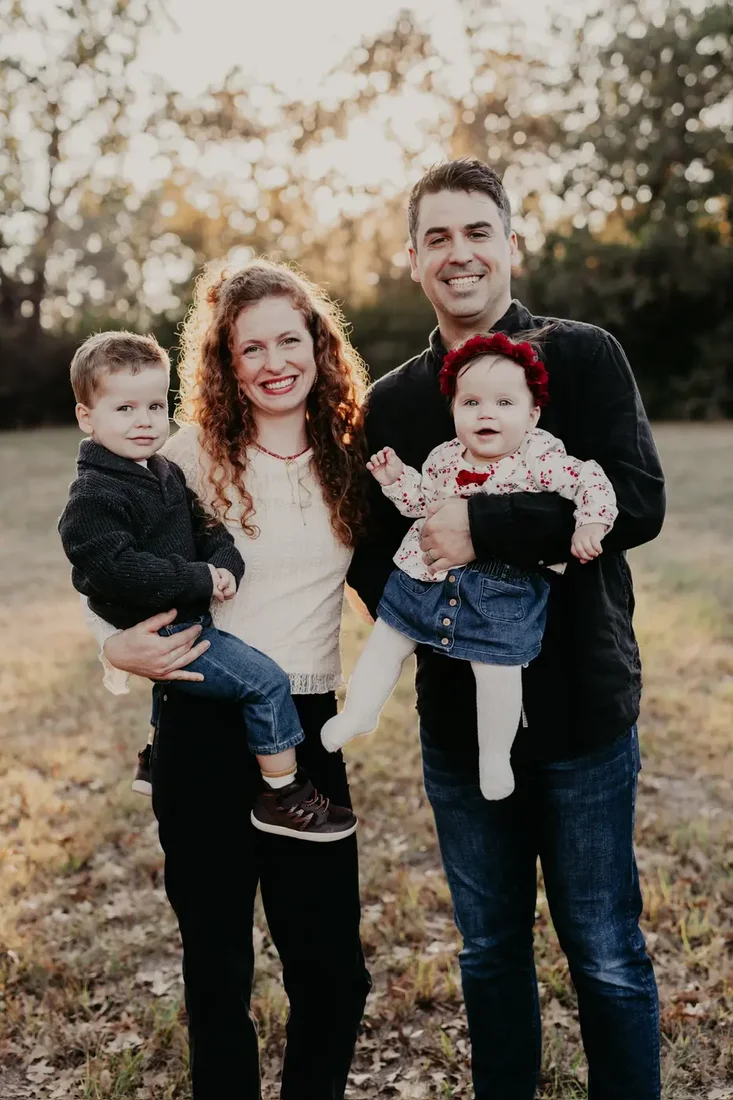 Family of four, father holding baby girl in a flower crown
