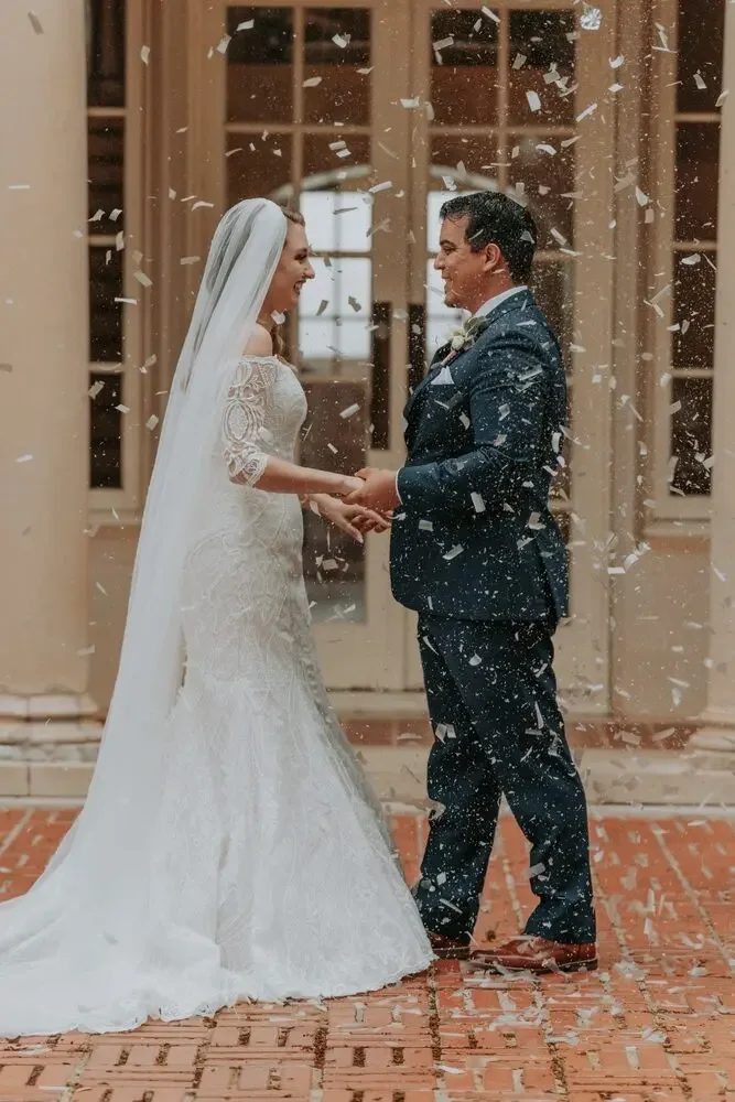 Bride and groom laughing in a shower of confetti