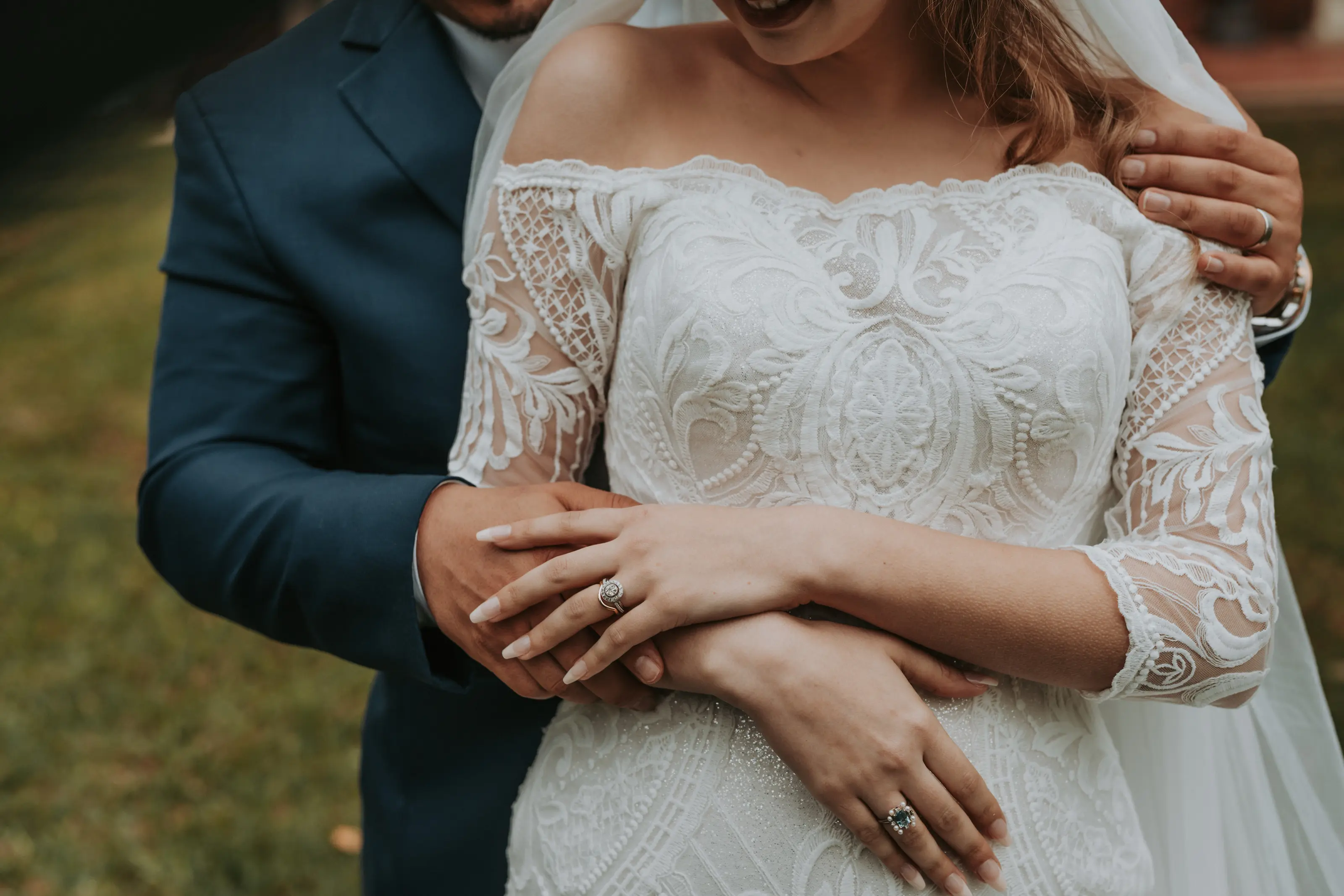 Bride and groom holding hands, wedding ring detail