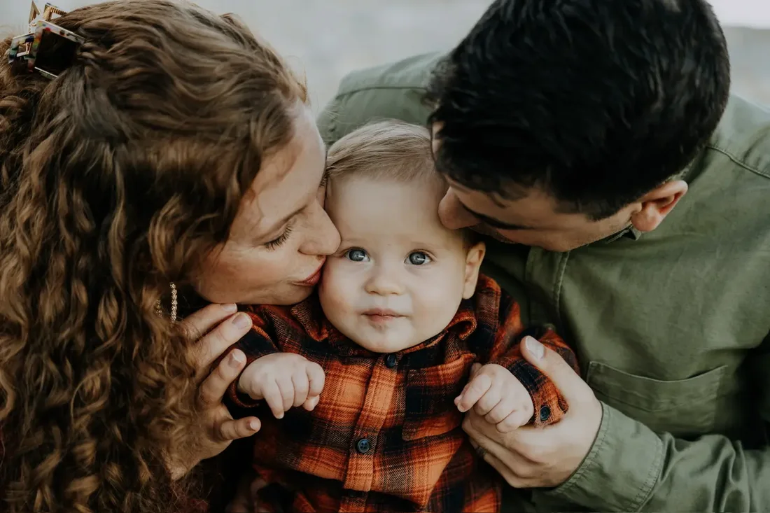 Parents kissing their baby on the cheeks