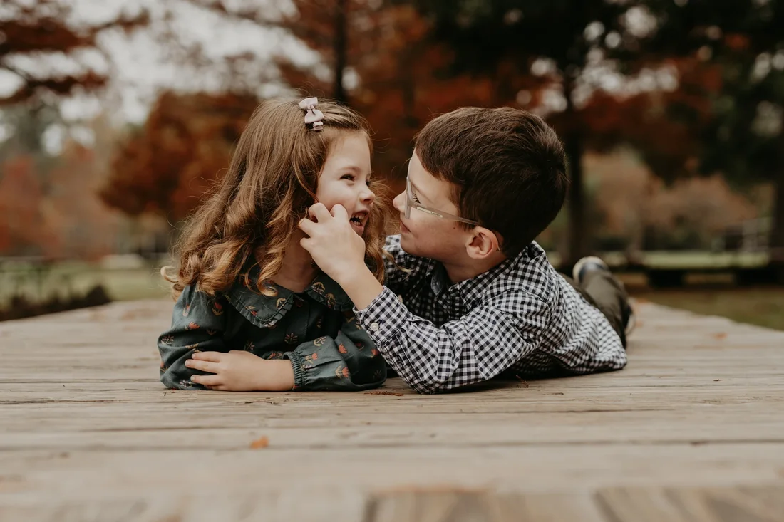 Brother and sister laughing together on a dock