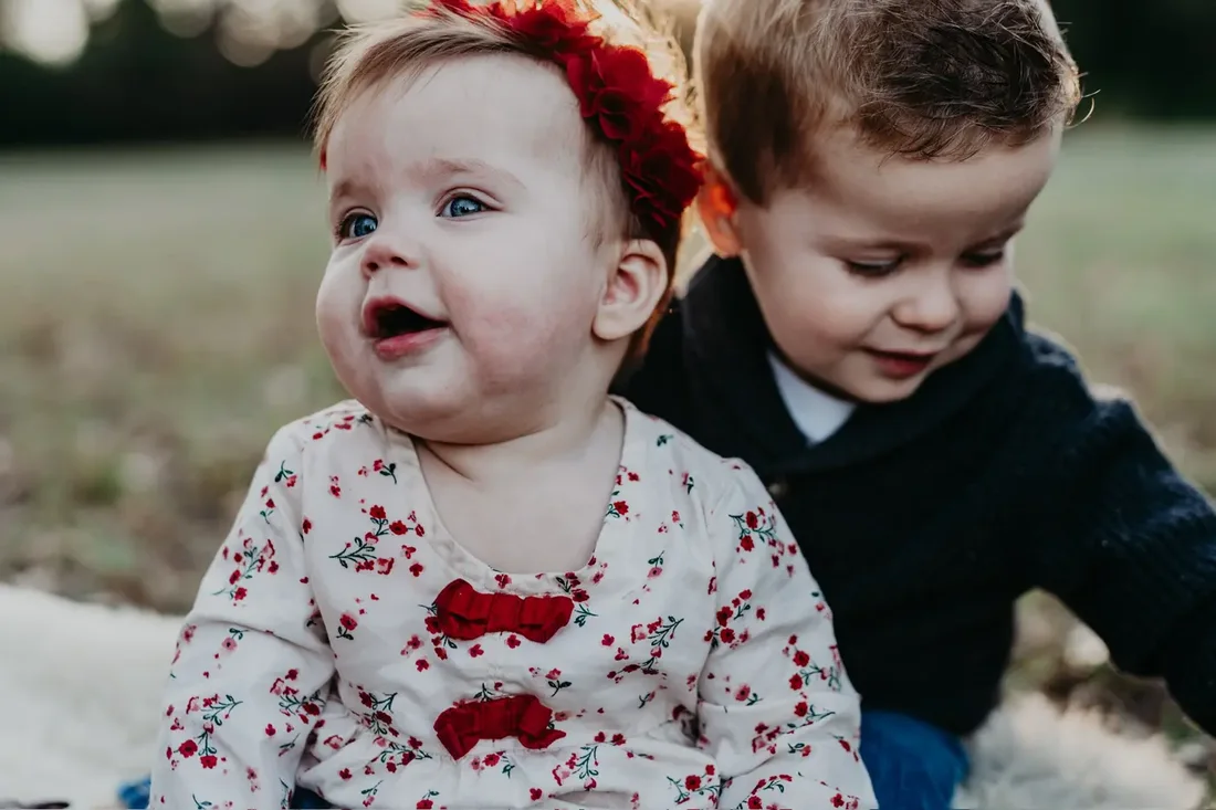 Baby and toddler sitting close together outdoors