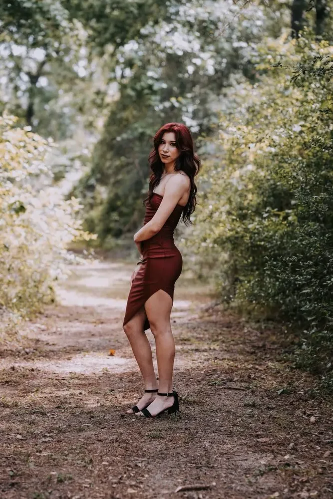 Senior portrait, woman in a red dress on a wooded path