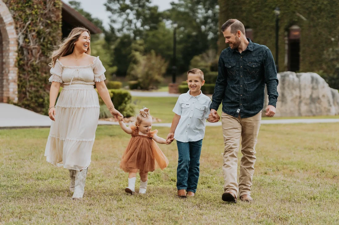 Family of four walking and laughing together outdoors
