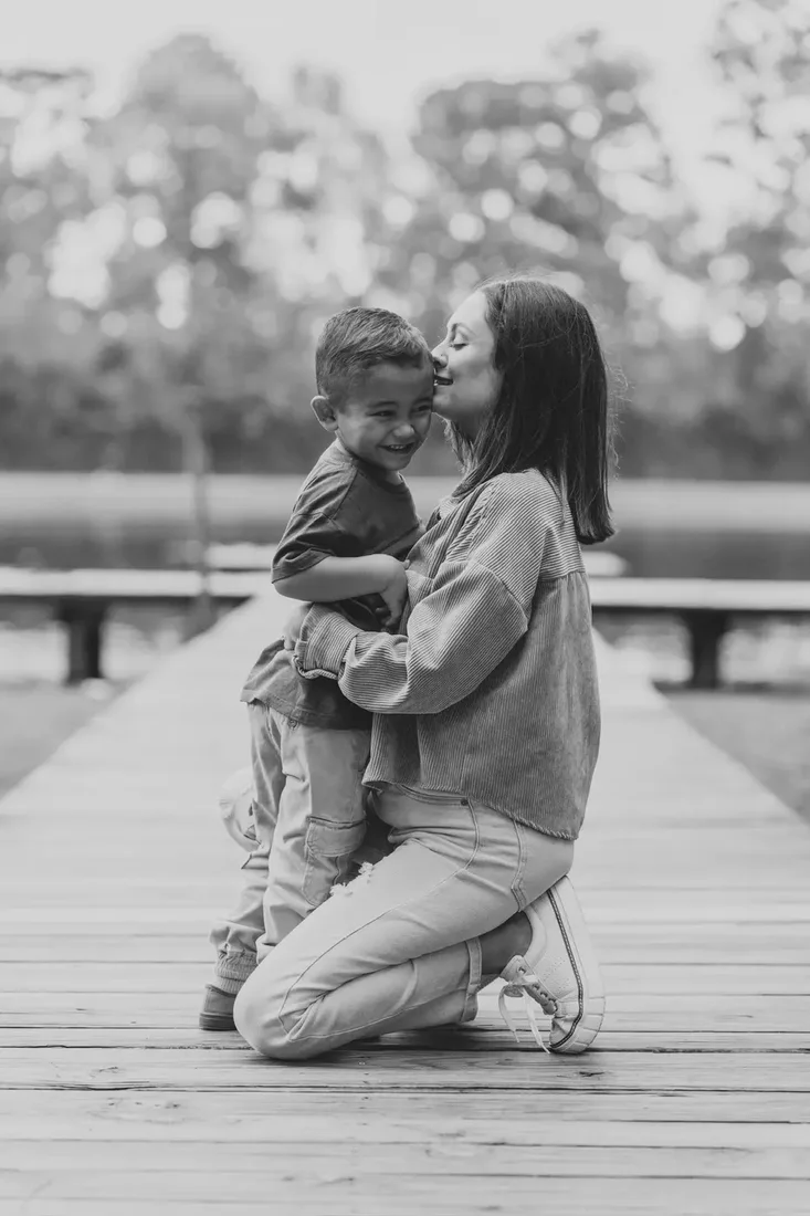 Mother kissing her son on a dock, black and white