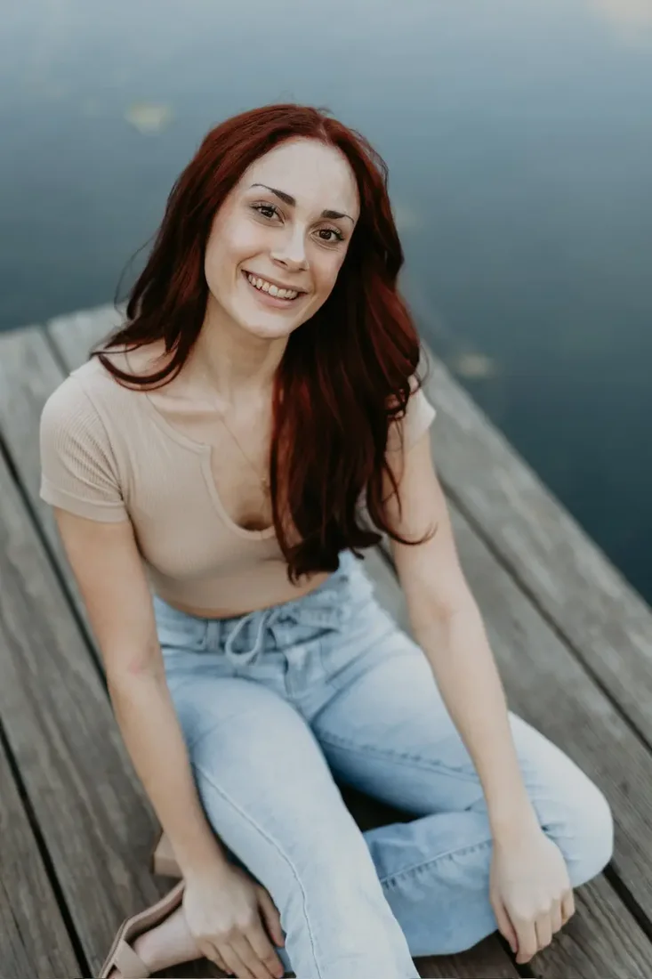 Senior portrait sitting on a dock smiling