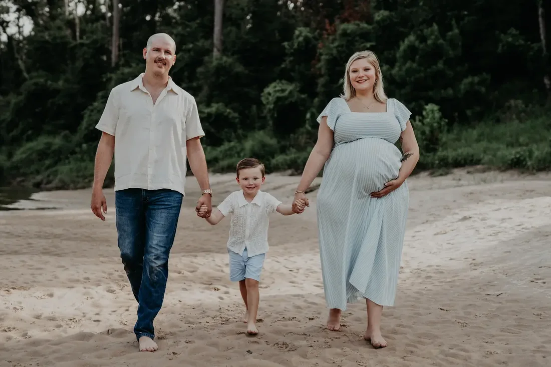 Family of three walking on the beach, mother expecting