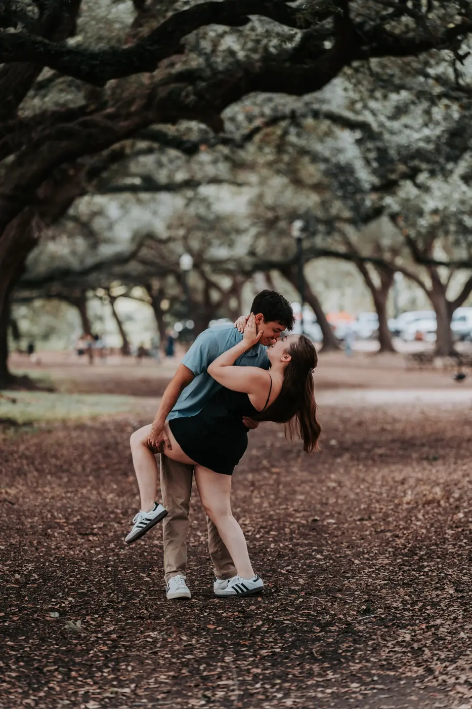 Couple sharing a dip kiss under oak trees at Hermann Park