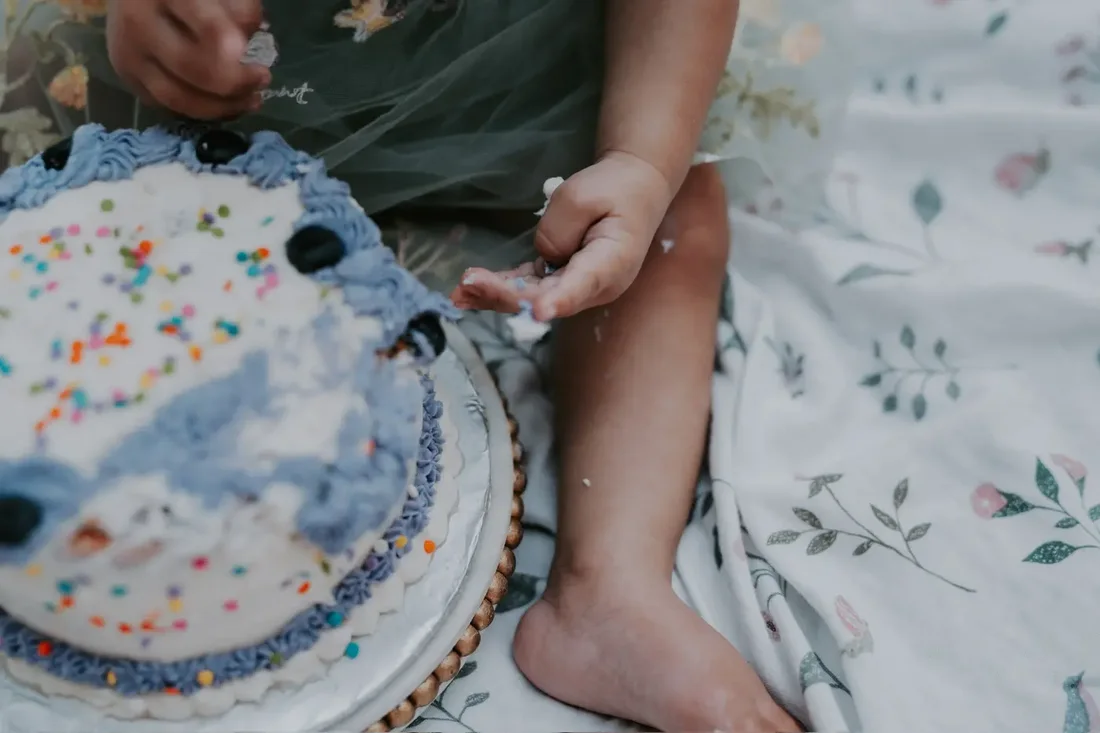 Detail of a child's hand reaching for birthday cake