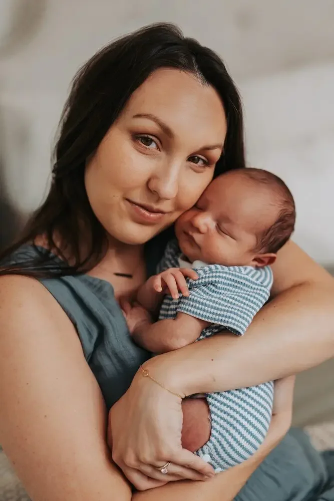 Mother smiling while holding her sleeping newborn