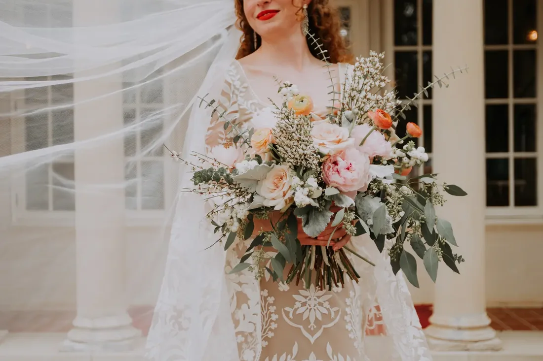 Bride's bouquet detail with veil blowing in the wind